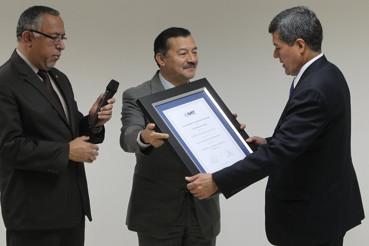 Francisco Rivera (centro), de la SAT, entrega certificado de calidad de depósito aduanero temporal a Carlos Lainfiesta, de la Empresa Portuaria Quetzal. (Foto Prensa Libre: Esbin García)