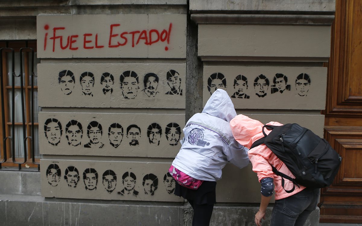 Dos personas pintan los rostros de los estudiantes desaparecidos, durante una manifestación en México. (Foto Prensa Libre: AP).