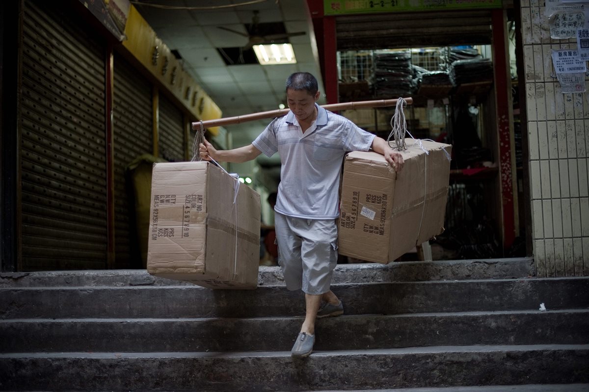Con varas de bambú los porteadores cargan los objetos más pesados (Foto Prensa Libre: AFP)