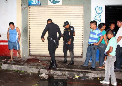 Agentes de la policía y curiosos observan la escena donde ocurrió el crímen. (Foto Prensa Libre: Rolando Miranda)