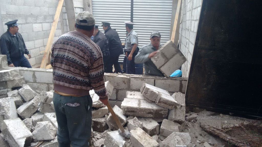 Policías ayudan a derribar pared de local, en Quetzaltenango. (Foto Prensa Libre: María José Longo).