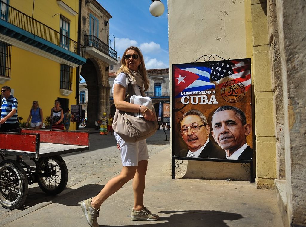 Una turista camina frente a un afiche que muestra la imagen del presidente de EE. UU., Obama, junto a la de su homólogo de Cuba, Raúl Castro. (Foto Prensa Libre: AFP).