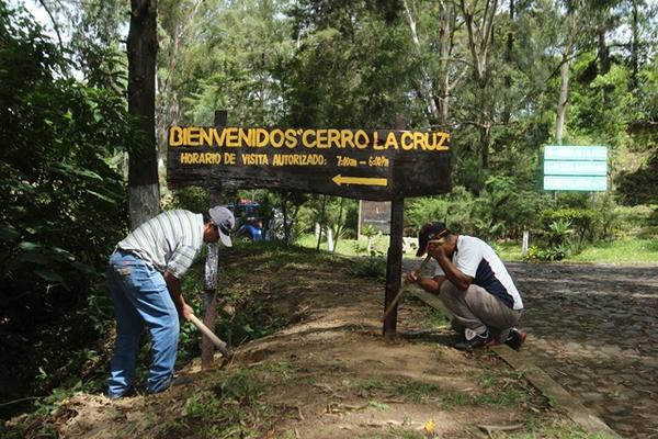 Dos empleados municipales colocan un rótulo en el Cerro de la Cruz, Antigua Guatemala. (Foto Prensa Libre: Miguel López) <br _mce_bogus="1"/>