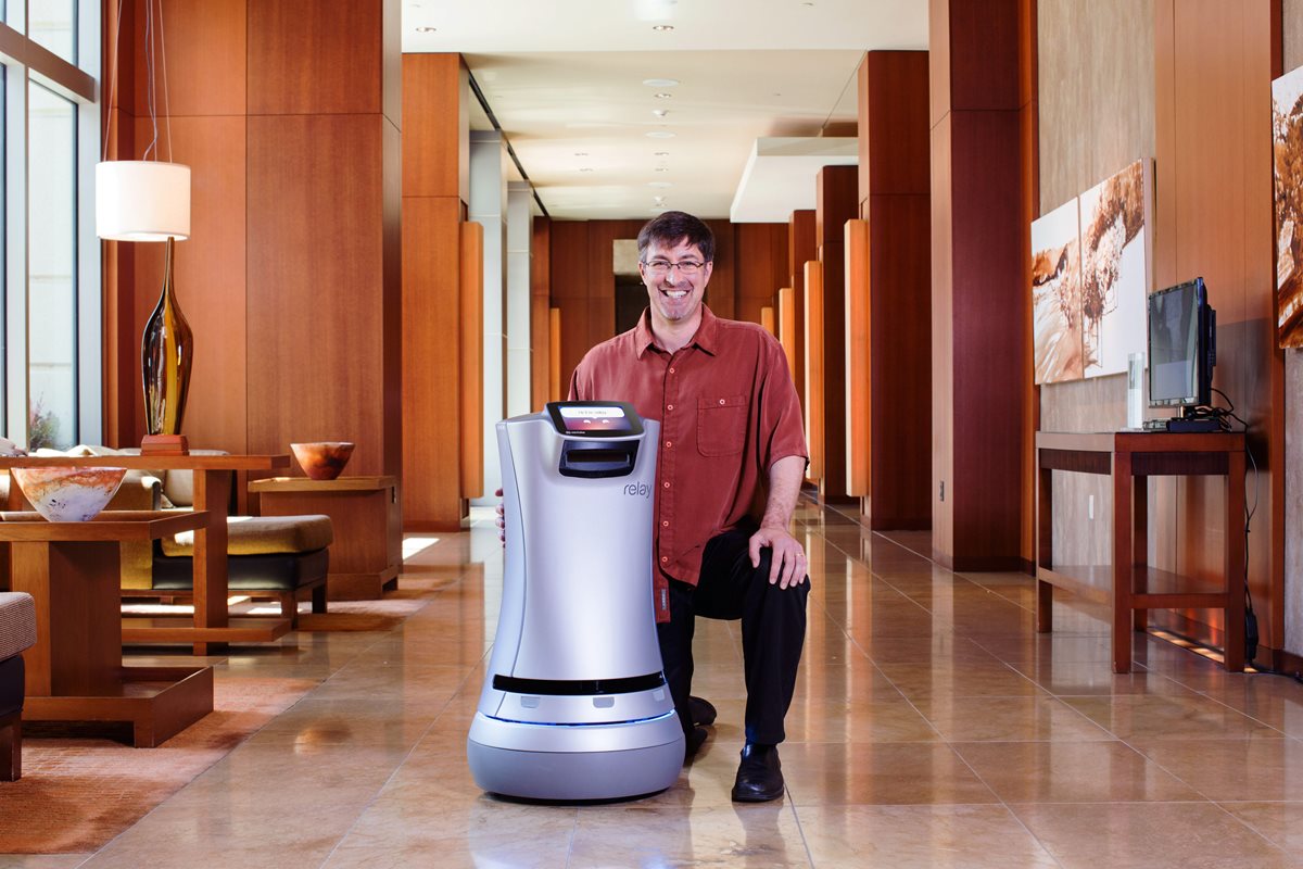 El robot "Relay" junto a Steve Cousins, Director  de la empresa Savioke, en el lobby de un hotel de Silicon Valley. (PL-EFE)