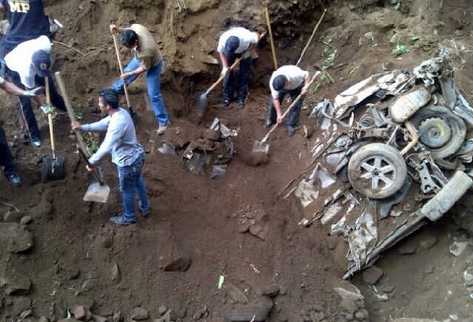 Bomberos voluntarios ayudan en  tareas de excavación, para retirar  tierra y piedras de uno de los automotores  que fueron encontrados.