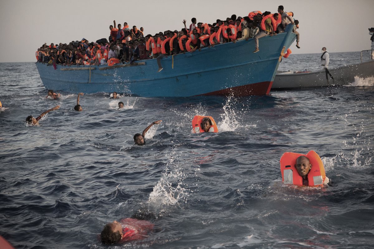 Migrantes desesperados se lanzan de bote a punto de zozobrar, en costa libia. (Foto Prensa Libre: AP)