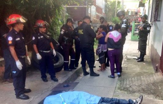Agentes de la PNC conversan con vecinos de la colonia Villalobos 1 en el lugar del crimen. (Foto Prensa Libre: CBM)