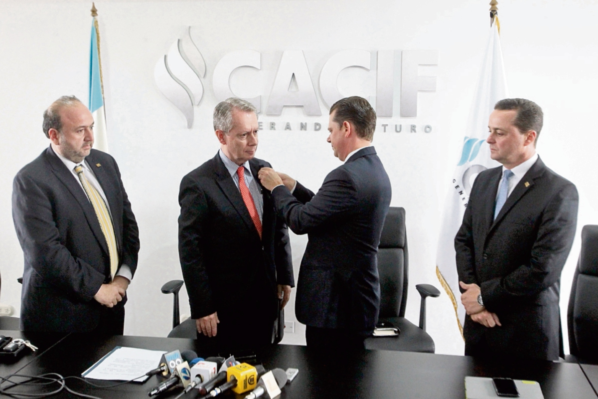 momento en  que Hermann Girón coloca a Jorge Briz  el pin de presidente del Cacif. Antonio Malouf —izquierda— y Pelayo Llarena —derecha— observan.