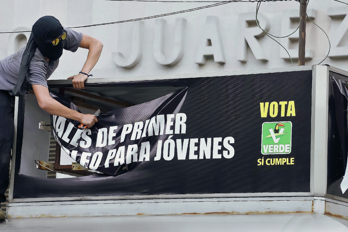 Un manifestante destroza una bandera electoral del Partido Verde durante una protesta en la ciudad de México. (Foto Prensa Libre:AFP).