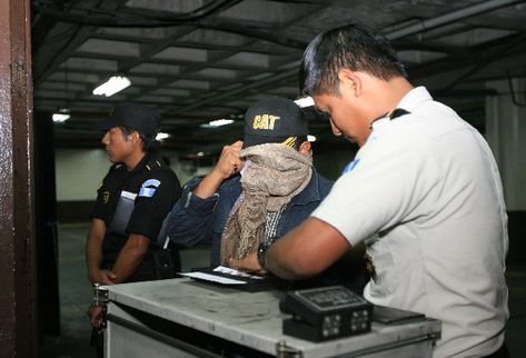 Agentes policiales  registran las huellas digitales de una persona detenida