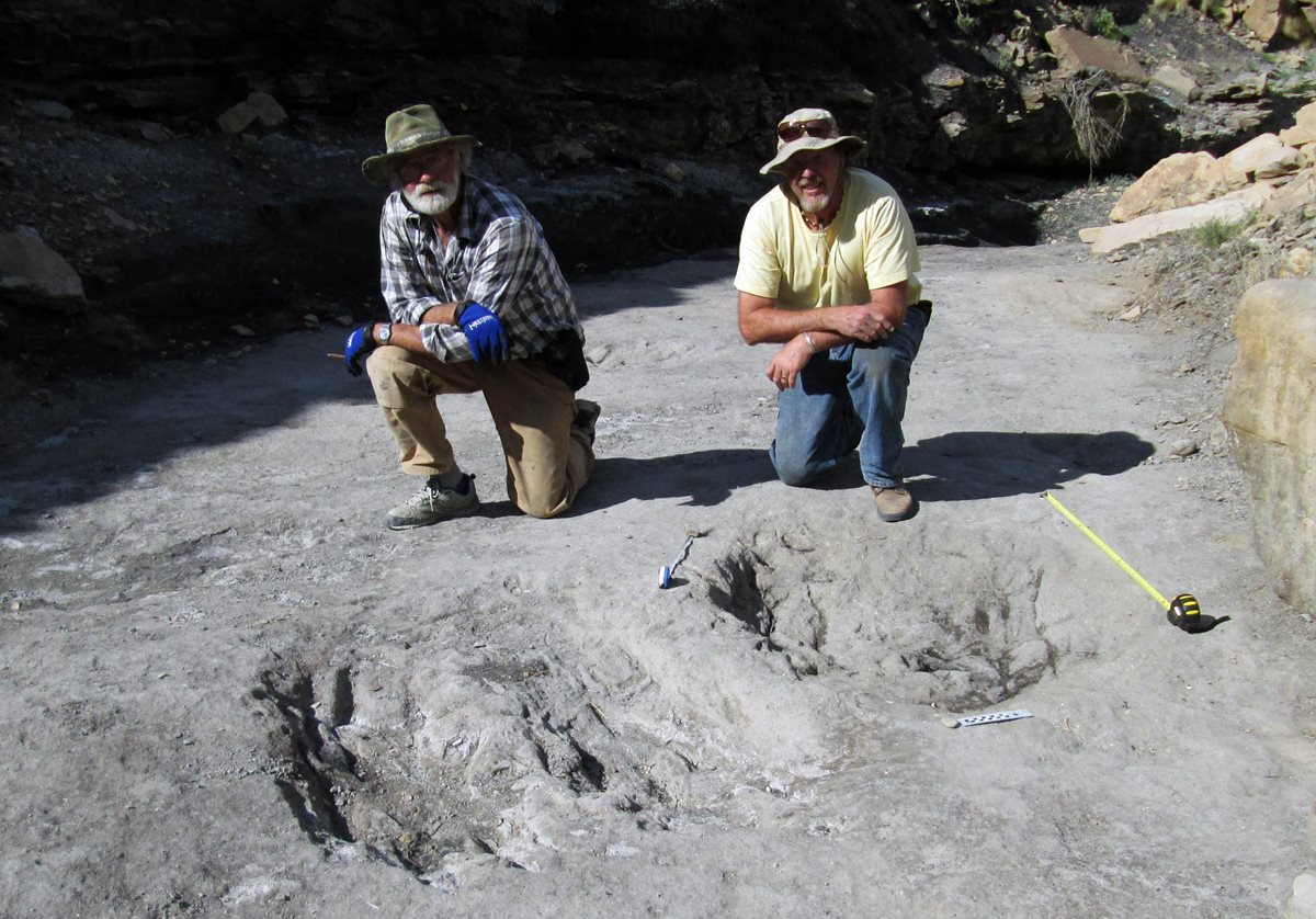 Dos científicos posan frente a las huellas encontradas en Colorado, EE. UU. (Foto Prensa Libre: AP).