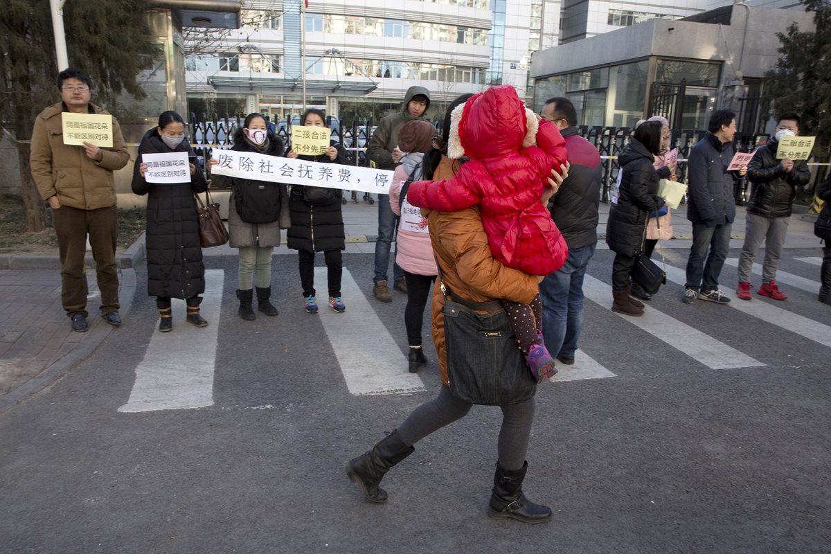 Padres que tuvieron hijos fuera de la norma de hijo único en el país protestan frente a la comisión de planificación familiar. (Foto Prensa Libre: AP).