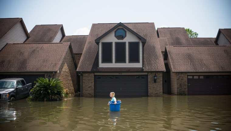 Jenna Fountain lleva un cubo para intentar recuperar los artículos de su hogar inundado Port Arthur, Texas. Los residentes de Houston y otras ciudades de Texas comenzaron a regresar a casa para evaluar los daños causados por el huracán Harvey.(Foto, Prensa Libre: AFP)