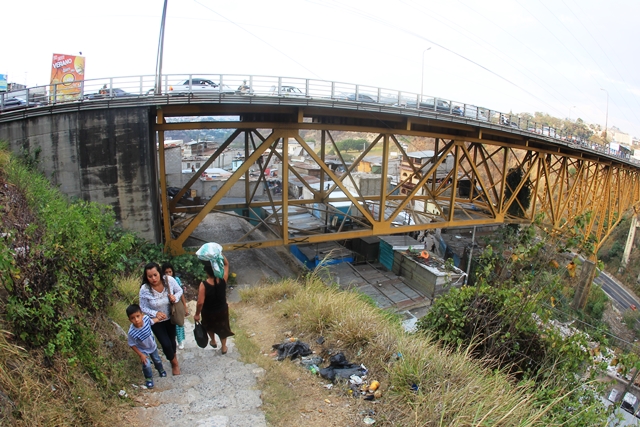 Las familias entran y salen del barrio a cualquier hora del día y retan el ruido, la vibración y la amenaza de la gigantesca estructura del puente Belice. (Foto Prensa Libre: Esbin García)
