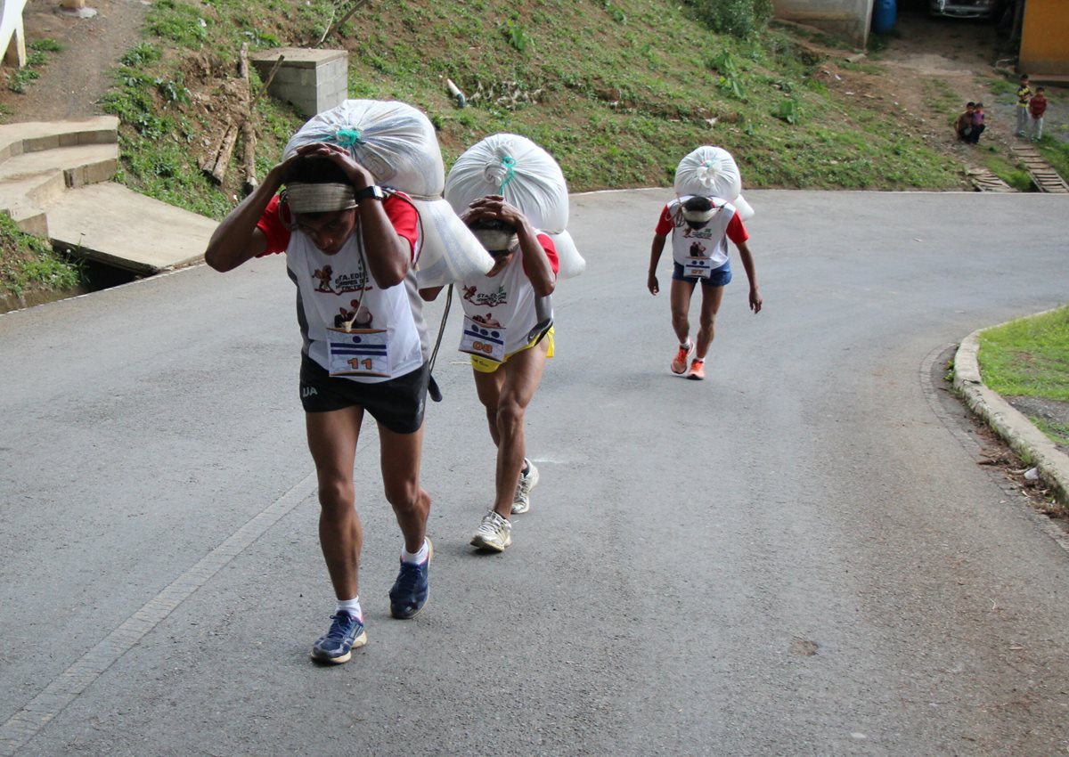 Tres participantes de la carrera de los Hombres de Maíz se esfuerzan por llegar a la meta, en Tactic, Alta Verapaz. (Foto Prensa Libre: Eduardo Sam Chun)