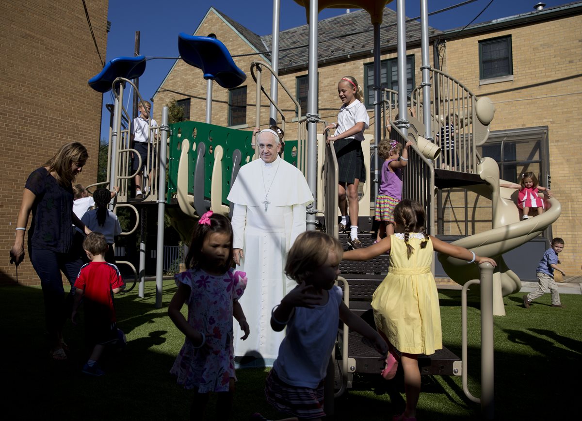Niños juegan junto a la imagen del Papa en una parroquia de Washington DC. (Foto Prensa Libre: AP)