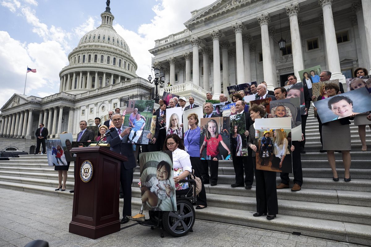 El senador demócrata por Nueva York, Chuck Schumer (en el atril) junto con otros senadores portan fotografías de aquellos pacientes se verían afectados por la reforma en la ley de Sanidad. (Foto Prensa Libre: EFE)