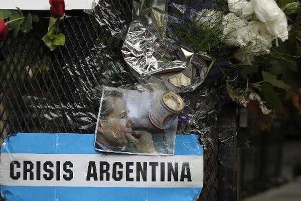 Un cartel que dice "crisis argentina" y una foto del fiscal argentino Alberto Nisman en Belgrano. (Foto Prensa Libre: AFP)