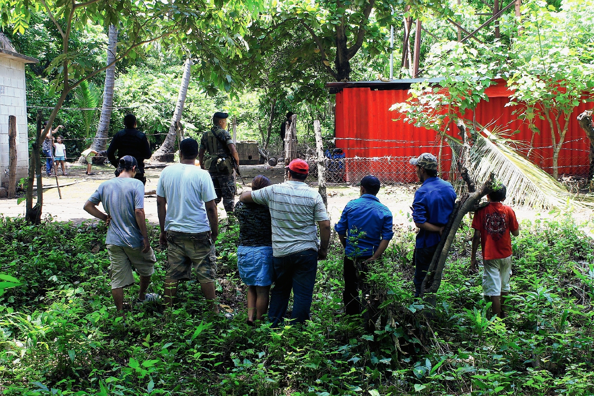 Curiosos permanecen en el lugar donde murió baleada Marta Elena Contreras, en Masagua, Escuintla. (Foto Prensa Libre: Enrique Paredes)