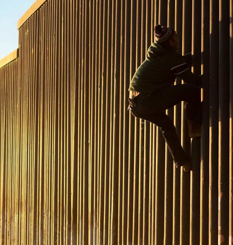 Un migrante hondureño escala el muro fronterizo entre México y Estados Unidos. (Foto Prensa Libre: AFP)
