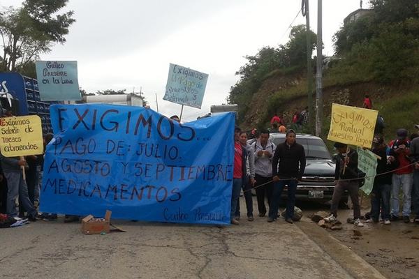 Con mantas y barreras humanas, salubristas bloquearon la ruta interamericana para exigir el pago de salarios atrasados. (Foto Prensa Libre: Mike Castillo).
