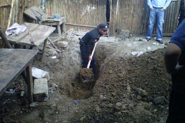 Un agente cava el área  donde fue localizado el cadáver del empresario español, en El Estor, Izabal.