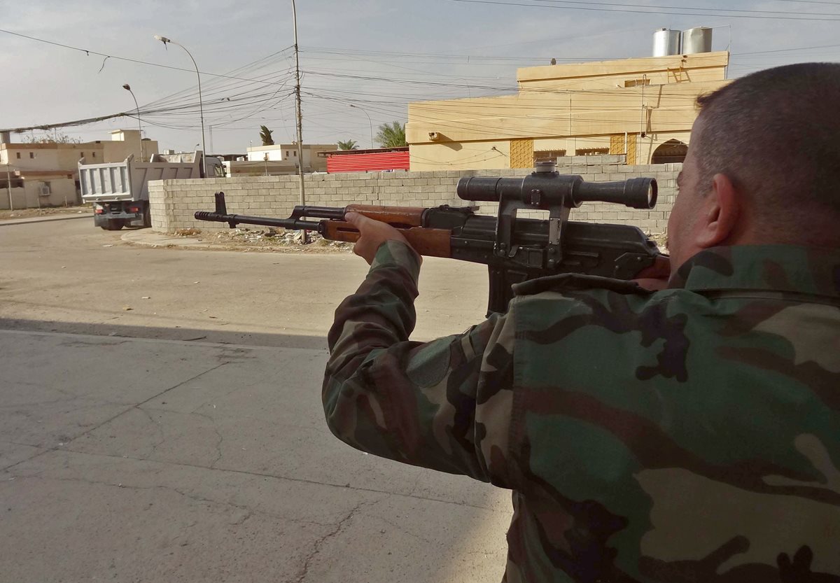 Un oficial del Ejército iraquí apunta con su arma un objetivo yihadista durante el ataque a Kirkuk. (Foto Prensa Libre: AFP).
