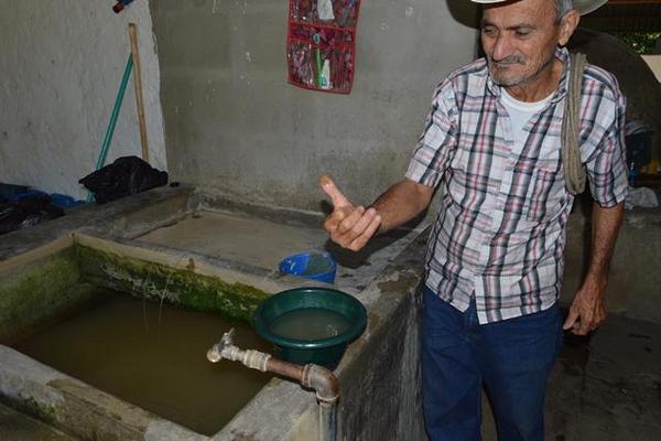 Gustavo Molina, vecino de la aldea El Terreno, muestra cuán sucia llega  el agua entubada a ese sector de la cabecera de Zacapa. (Foto Prensa  Libre: Víctor Gómez)