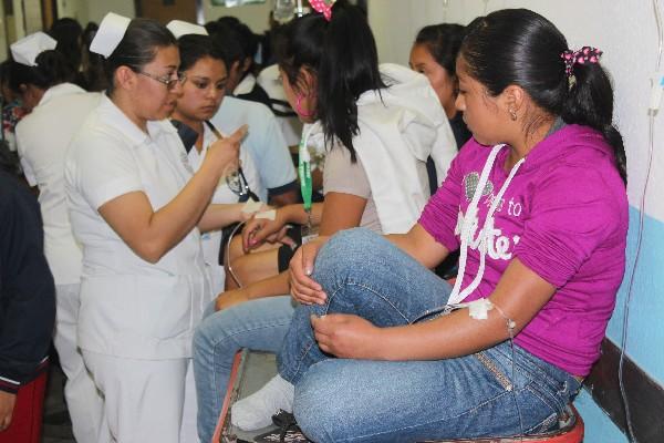 Dos enfermeras evalúan  a una de las jóvenes que resultó afectada por alimentos en mal estado.