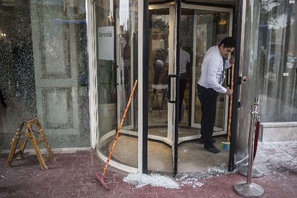 Un empleado del hotel limpia los cristales rotos después del ataque. (Foto Prensa Libre:AFP).