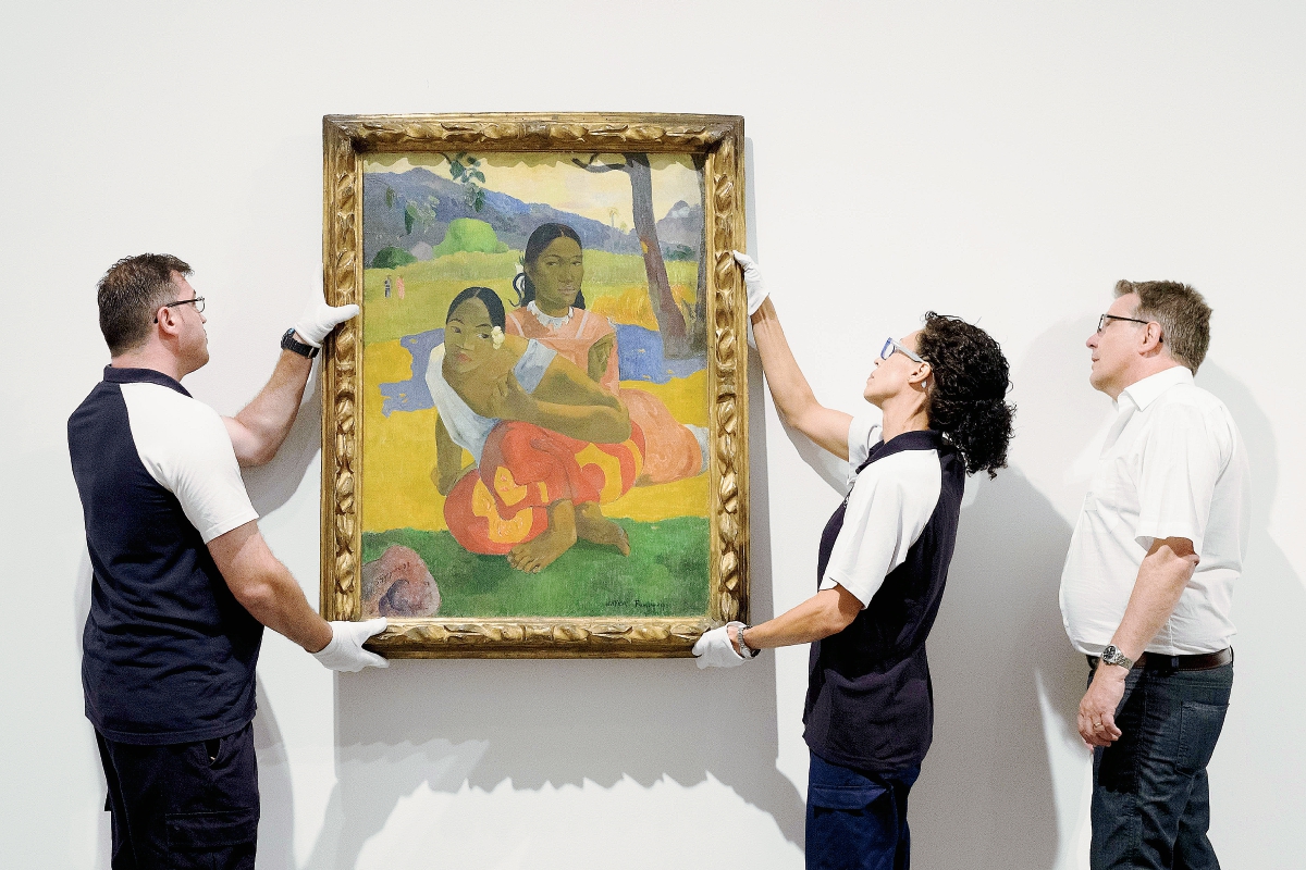 Dos empleados del Museo Reina Sofía instalan el cuadro de Paul Gauguin's "Nafea Ipoipo faa", la obra más cara vendida del mundo. (Foto Prensa Libre, AFP)
