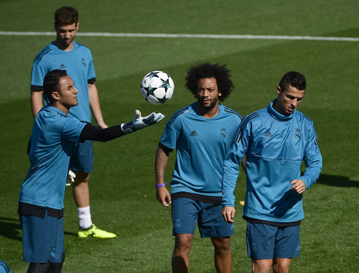Keylor Navas sostiene el balón mientras es observado por Marcelo y Cristiano Ronaldo en la última practica del Real Madrid antes de recibir al Apoel en la Champions League. (Foto Prensa Libre: AFP)