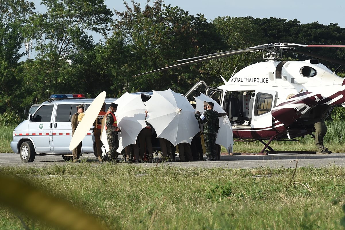 Efectivos de la Policía y militares usan sombrillas para cubrir a uno de los rescatados y ser trasladado en helicóptero en Chiang Rai. (Foto Prensa Libre:AFP)