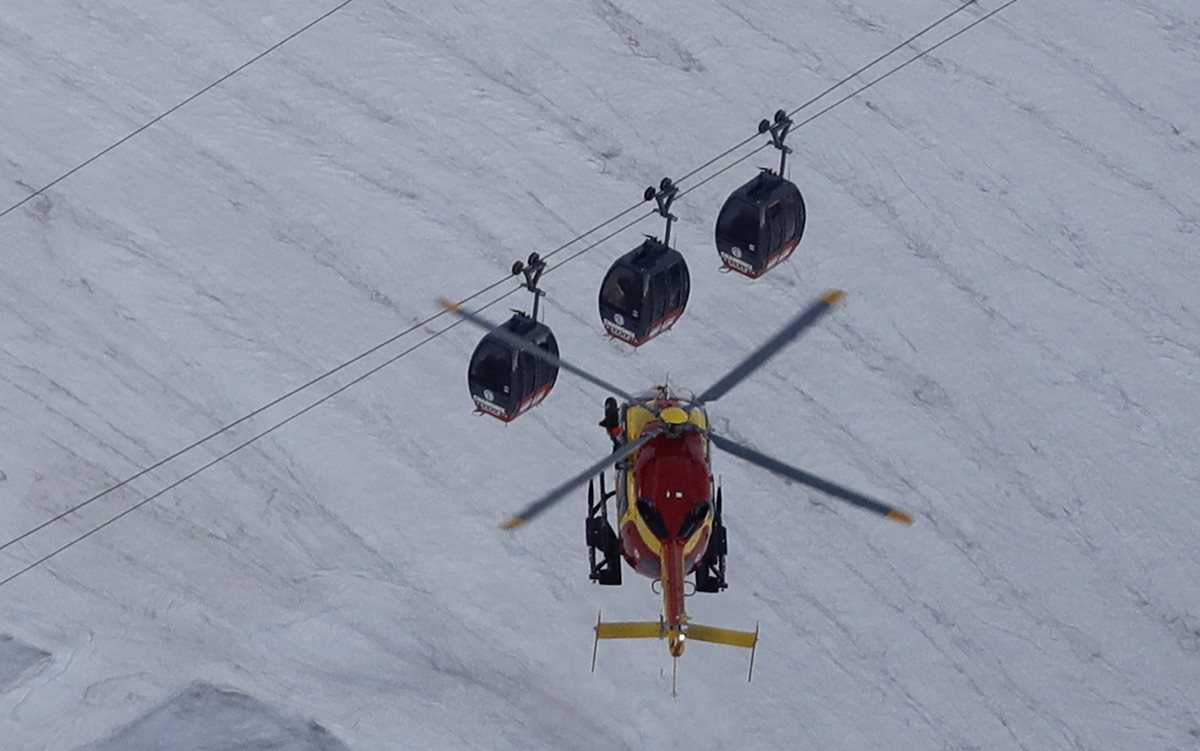 Un helicóptero se aproxima a tres cabinas del teleférico que se averió en los Alpes franceses. (Foto Prensa Libre: AFP).