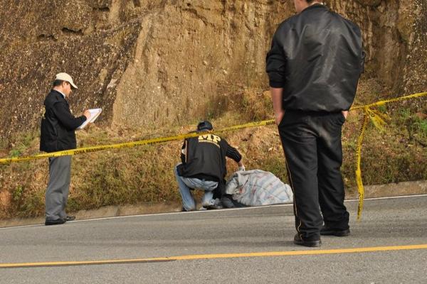 Fiscales del Ministerio Público inspeccionan el cadáver de un hombre envuelto en una frazada, que fue localizado en Santa Cruz del Quiché. (Foto Prensa Libre: Oscar Figueroa)<br _mce_bogus="1"/>