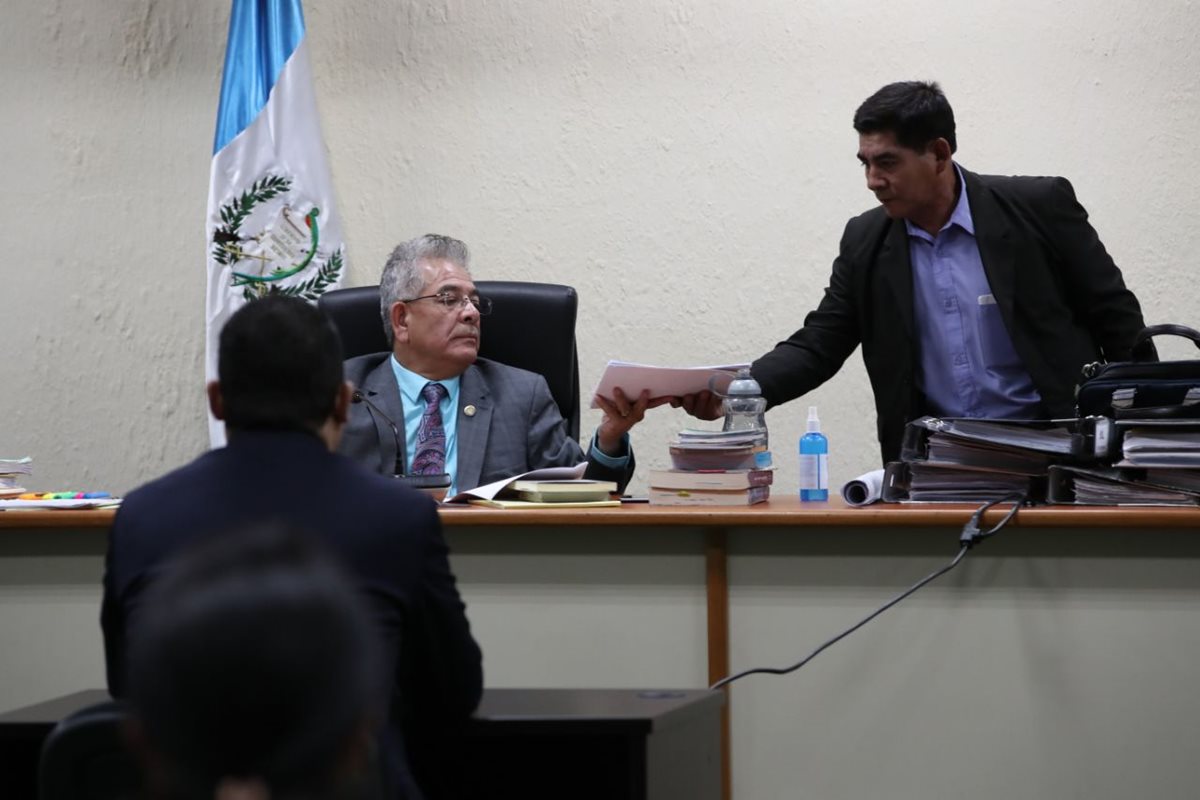 Momento en que el juez Miguel Ángel Gálvez entrega fotografías de la vivienda de Juan Carlos Monzón que fue violentada por sujetos armados. (Foto Prensa Libre: Paulo Raquec)