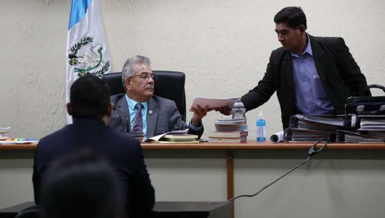 Momento en que el juez Miguel Ángel Gálvez entrega fotografías de la vivienda de Juan Carlos Monzón que fue violentada por sujetos armados. (Foto Prensa Libre: Paulo Raquec)