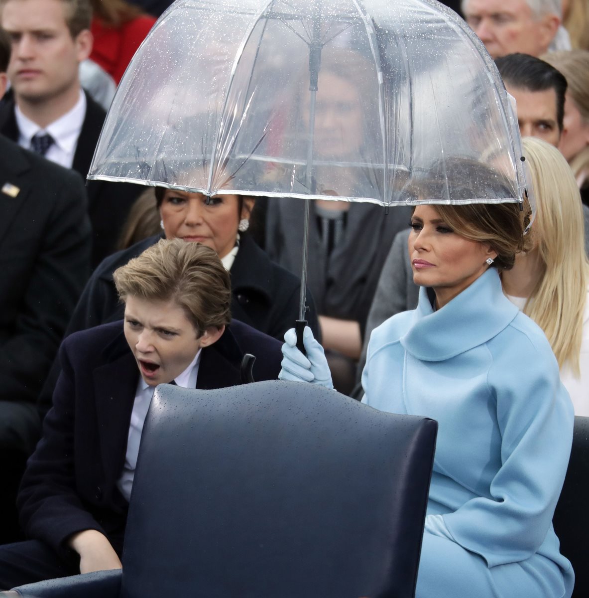 Barron Trump bosteza mientras su madre, Melania Trump, lo protege de la llovizna que cayó durante la ceremonia de toma de posesión. (Foto Prensa Libre: AFP)
