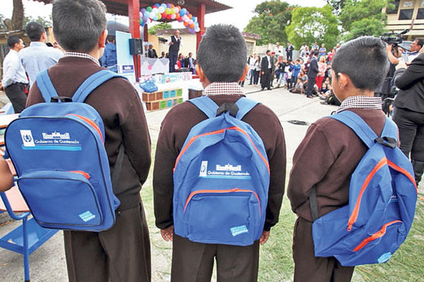 Estudiantes llevan mochilas azules con detalles anaranjados entregadas ayer en acto oficial para iniciar el ciclo escolar.