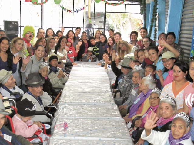 Ancianos disfrutan, junto a voluntarios, un momento de alegría, durante la convivencia organizada por las fiestas de fin de año en el asilo San José.