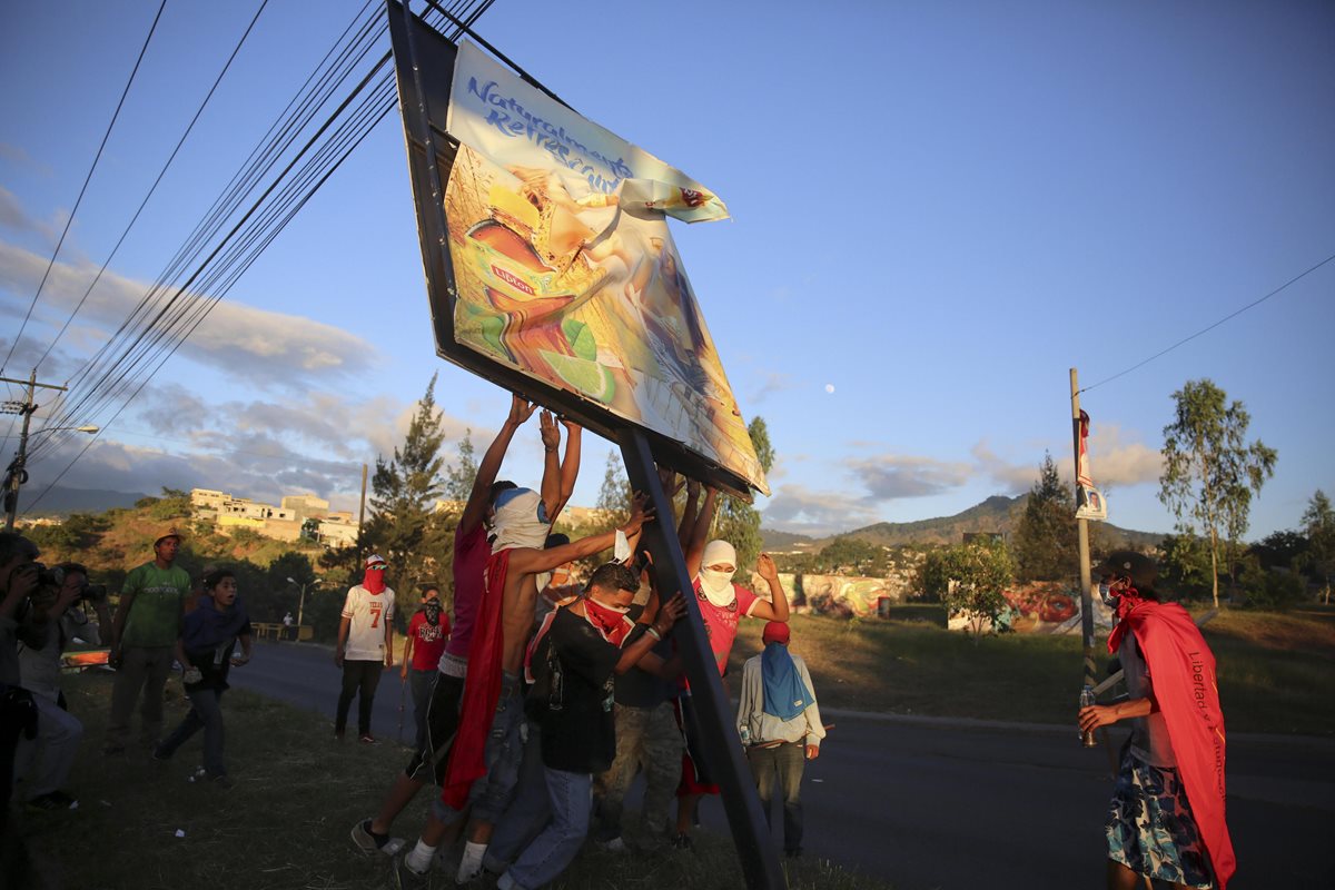Un grupo de manifestantes destruye una valla en Tegucigalpa, Honduras vive un ambiente de máxima tensión