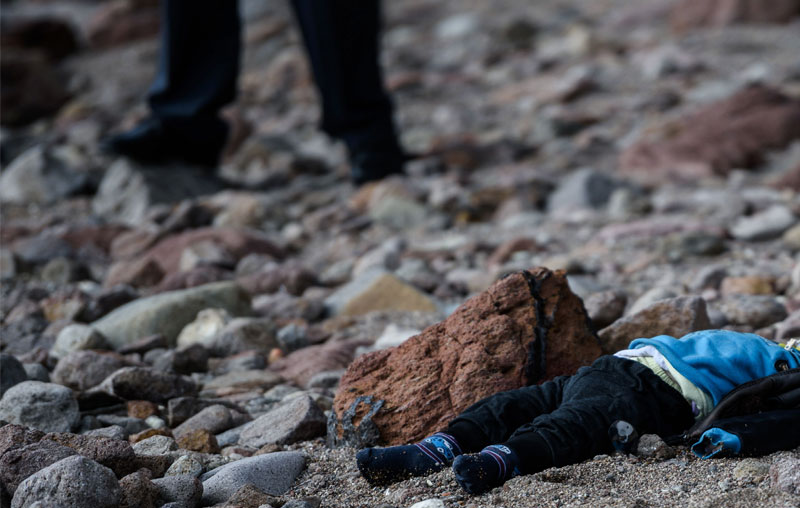 Policías turcos colocan el cuerpo de un niño ahogado en la costa de Canakkale. (Foto Prensa Libre: AFP).