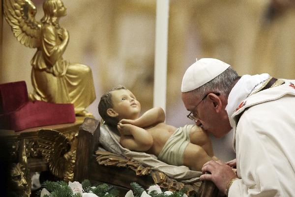El papa Francisco besa una escultura del Niño Jesús hoy, antes de dirigir la tradicional misa de medianoche en Navidad. (AP)