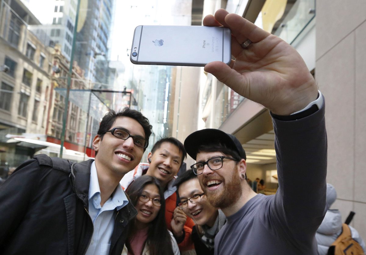  Un empleado de Apple posa para un selfi con varios clientes con un iPhone 6S, en Australia.  (PL-EFE)