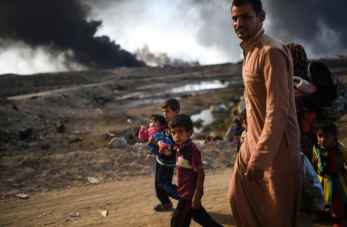 Un padre camina al sur de Mosul junto a sus hijos luego de ser desplazados por la operación en curso por las fuerzas iraquíes contra los yihadistas del Estado Islámico. (Foto Prensa Libre: AFP).