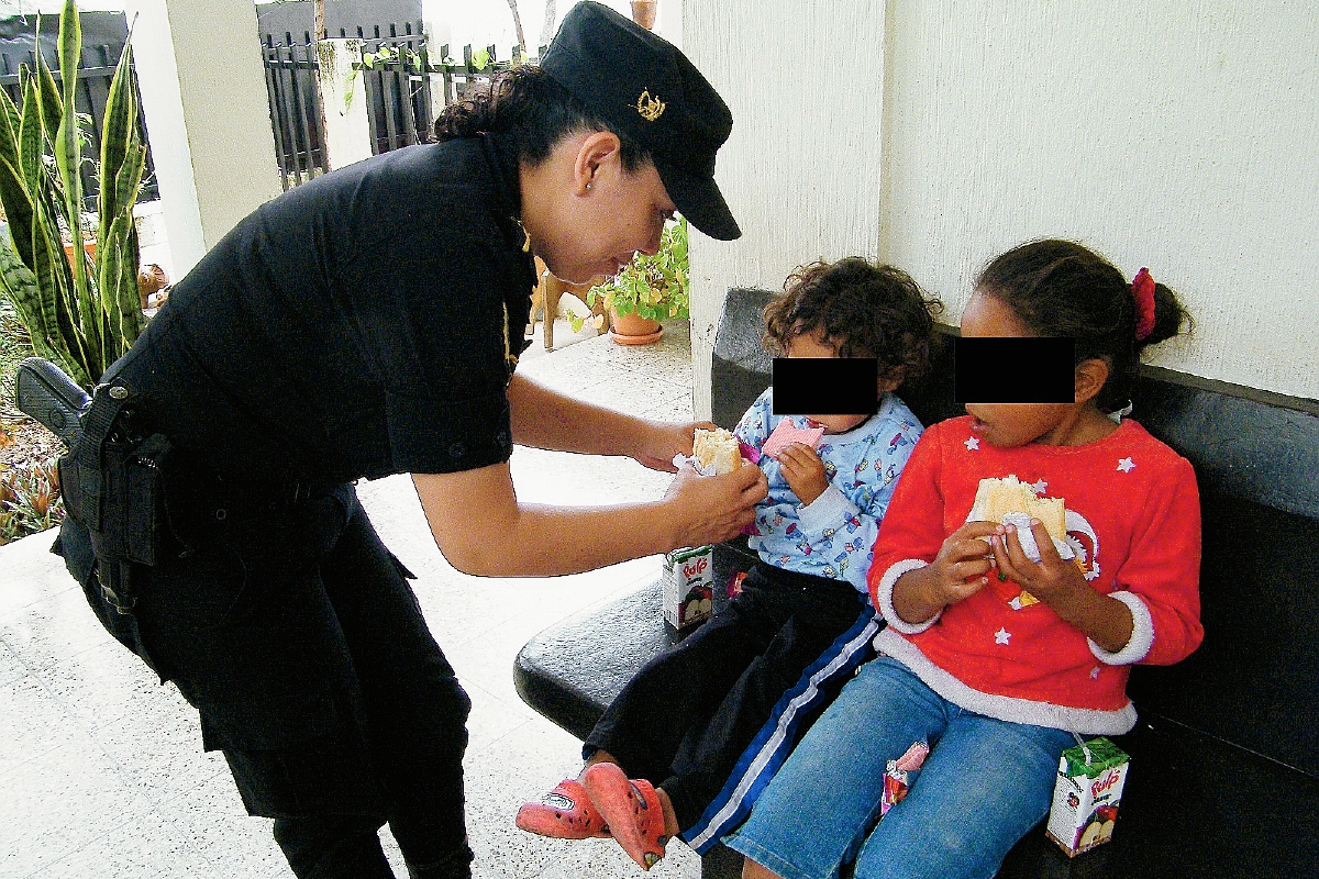 Una agente de la PNC le da alimentos a las niñas rescatadas en una vivienda de San Antonio La Paz, El Progreso. (Foto Prensa Libre: Héctor Contreras)