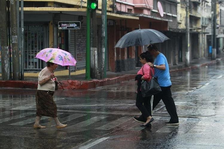 Personas caminan en una calle de la zona 1 durante una tarde de lluvia (Foto Prensa Libre: Hemeroteca PL)