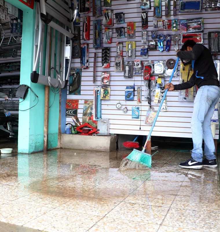 Comerciantes y vecinos de La Ciénaga, zona 2 de Xela, limpian el lodo que ingresó a sus viviendas la noche del miércoles último. (Foto Prensa Libre: Carlos Ventura)