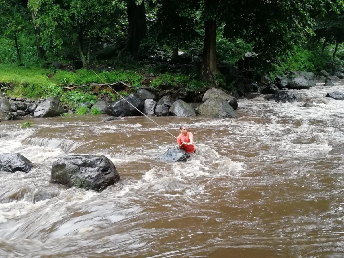 Uno de los turistas cruza el río Cantil, en Escuintla, donde los Bomberos Voluntarios colocaron cables para facilitar el rescate. (Foto Prensa Libre: Carlos Paredes)