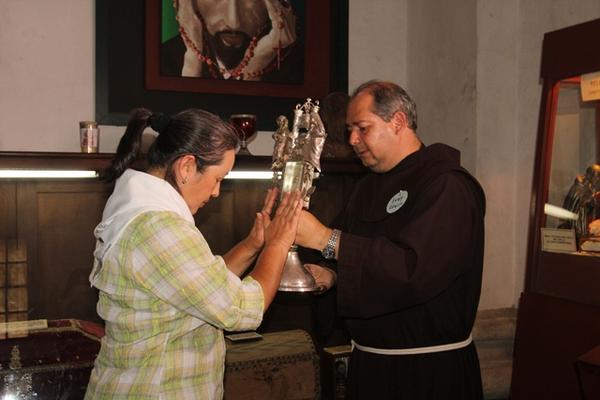 Una peregrina toca la custodia que contiene el fragmento de una costilla del Santo Hermano Pedro; la sostiene el frayle Edwin Alvarado. (Foto Prensa Libre: Miguel López)